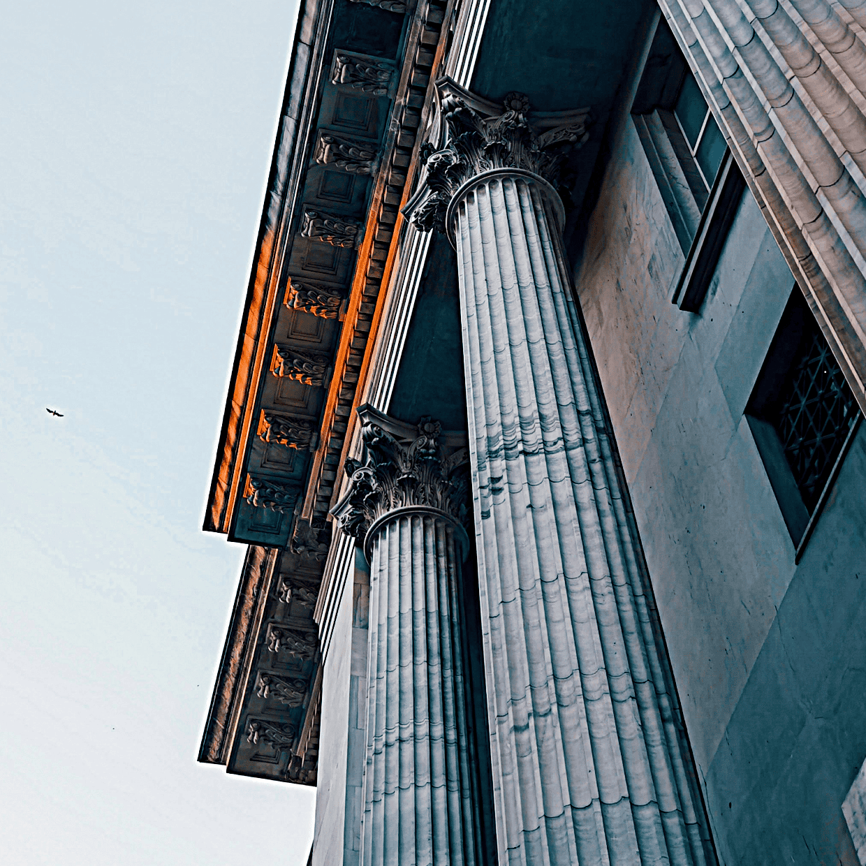 Upward view of tall stone columns and ornate classical architecture on a historic building.