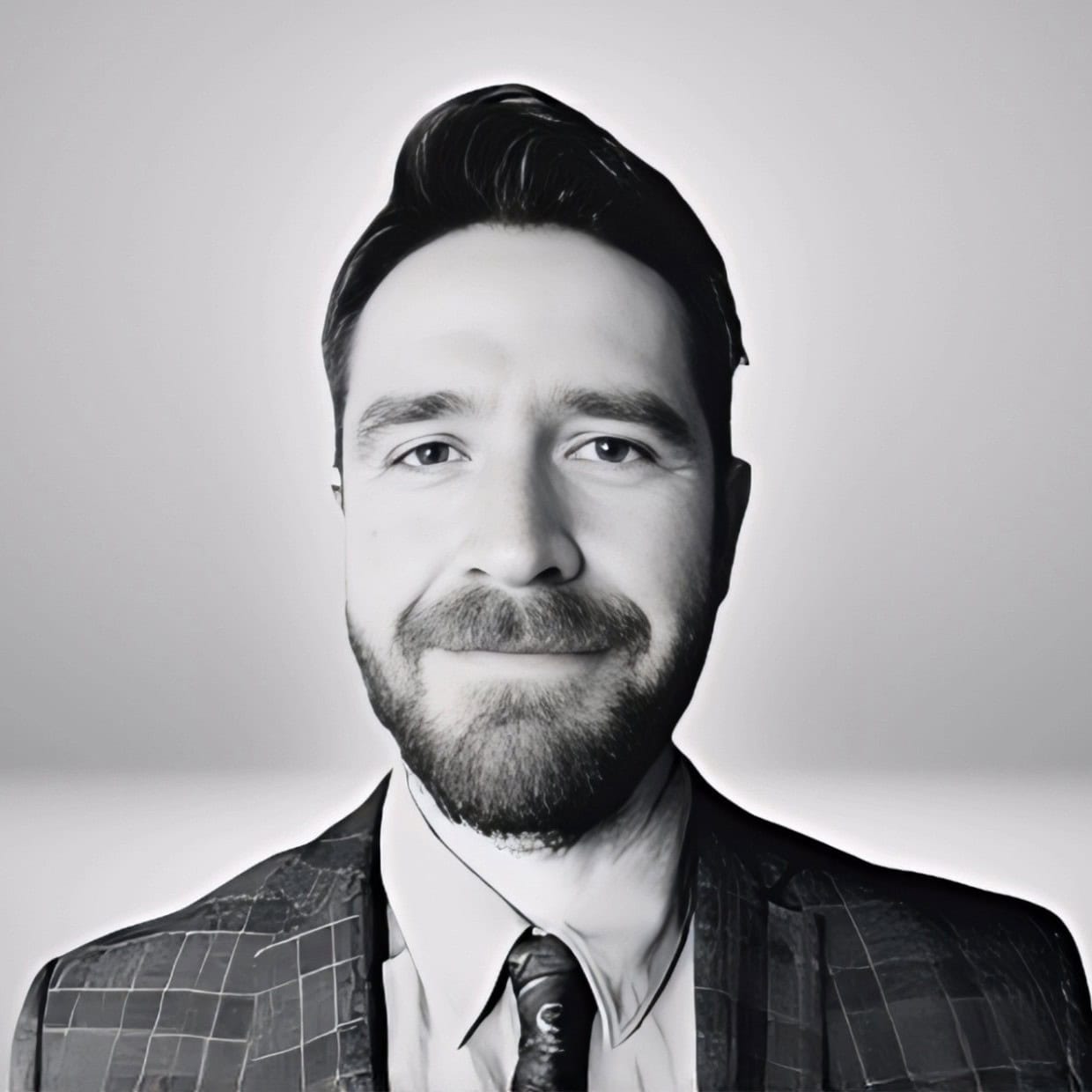 Black and white portrait of a smiling man in a patterned suit jacket and tie against a plain background.