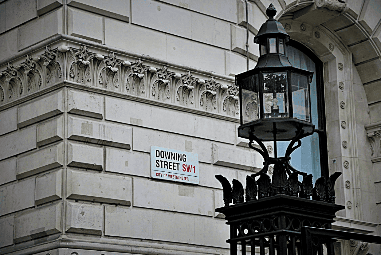 Street sign reading “Downing Street SW1” on a stone building in Westminster, with a traditional black lantern in the foreground.
